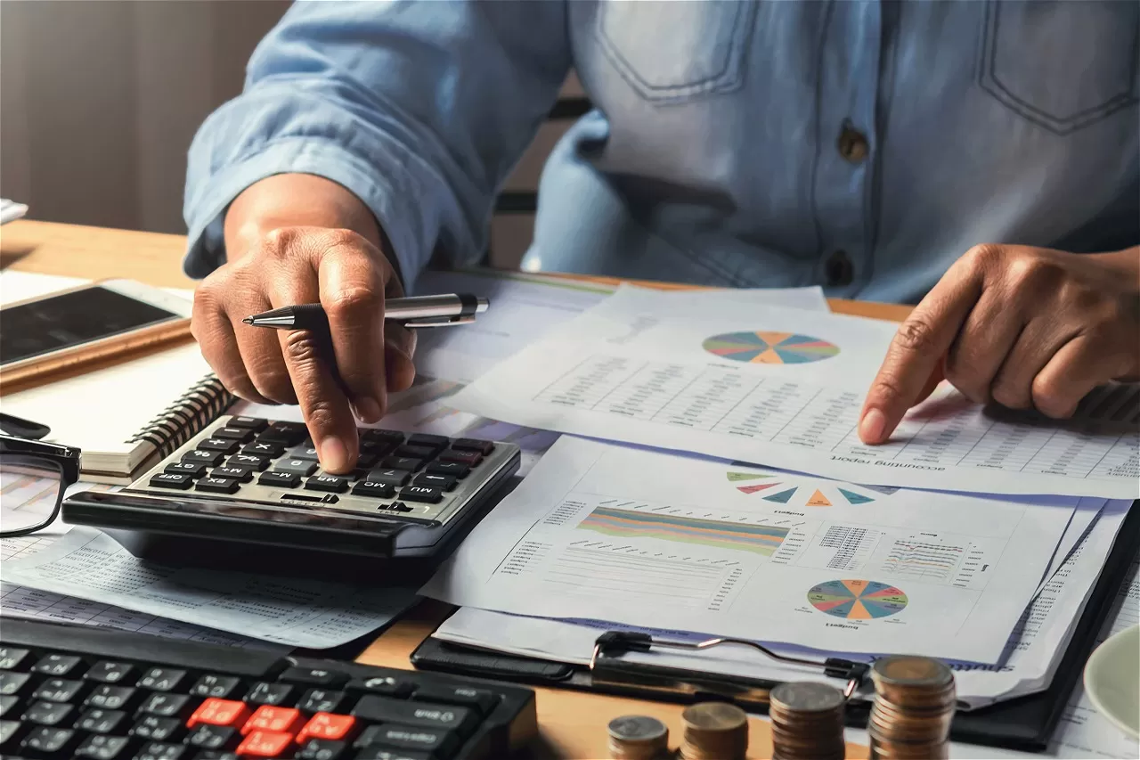 Accountant calculating with calculator and documents on desk
